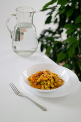 Italian pasta with shrimp and turmeric on a white table in a white plate