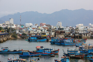 Fototapeta na wymiar A skyline of the coastal Vietnamese town of Nha Trang with boats in the harbour and the hills beyond.