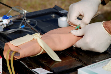 An emergency medicine doctor practicing placing an IV in an arm
