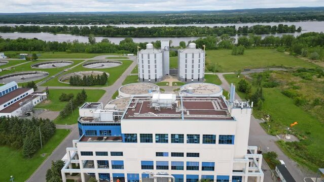 Drone shot flying over water treatment plant pump station with waste being burned off beside Ottawa River