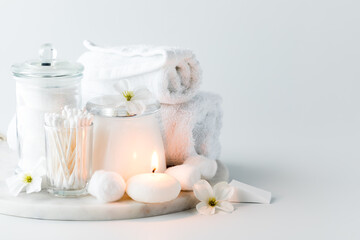 An arrangement of cleansing items with a lit candle glowing in front.