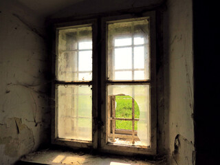 Fototapeta na wymiar Broken window in abandoned old building with dreamy, forgotten feeling