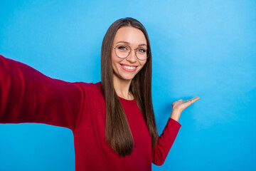 Photo of sweet millennial lady do selfie hold advert wear eyewear burgundy pullover isolated on blue color background