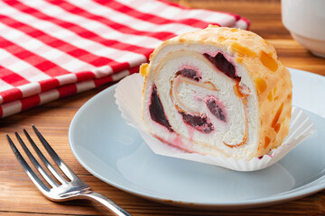 Meringue roll cake with cream on wooden table
