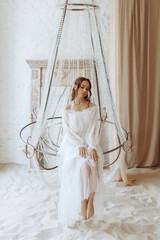 Fashion style portrait. An elegant woman sitting on a large beautiful chandelier. Spring concept. 
