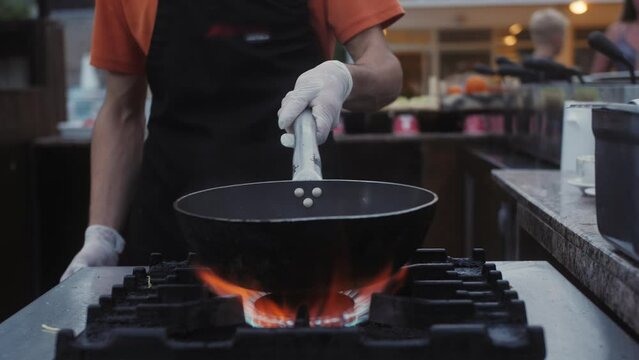 Chef working on wok with a flame, heat mixing mixed colorful vegetables, tossing.