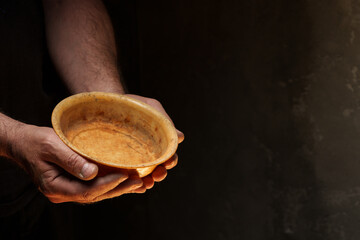 Male hands holding empty plate on dark background, lack of food, hunger concept.