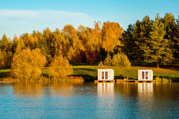 Fall season landscape with floating grey cabins on the lake