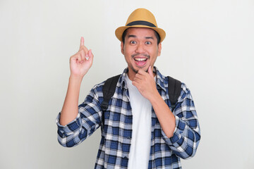 Asian man showing enthusiastic expression with right hand pointing up