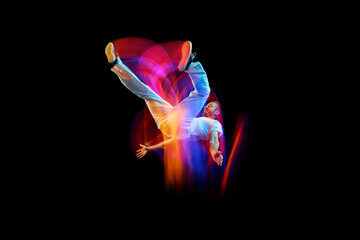 In miracle flight. Young sportive dancer in white clothes levitating, moving over dark background...