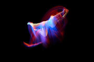 In miracle flight. Young sportive dancer in white clothes levitating, moving over dark background...