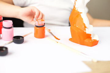 Obraz na płótnie Canvas a little girl paints a toy fox made of clay. DIY concept