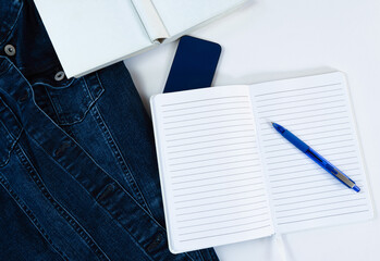 Aufgeschlagenes weißes liniertes Notizbuch mit blauem Kugelschreiber darauf, Draufsicht, weißer...