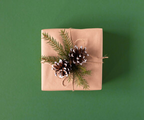 A gift in craft paper with a spruce branch and a cone for Christmas New Year
