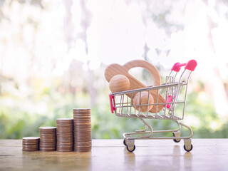 Wooden toy car in a shopping cart and stack of coins. Saving money for buy a car in the future
