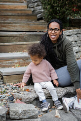 Biracial mom sitting with twins on steps in backyard in fall