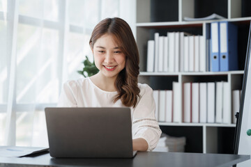 Smile Pretty business Asian woman freelancer is working her job on a laptop computer in a modern office. Doing accounting analysis report real estate investment data, Financial and tax systems concept