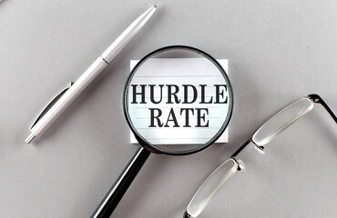 Word HURDLE RATE on sticky through magnifier on grey background