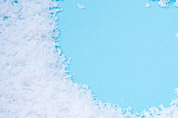 Close-up white polystyrene grain texture on blue background with space for text.