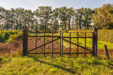 Simple iron gate between two wooden beams. The gate is in front of a small allotment complex in the outskirts of the Dutch city of Breda, in the province of North Brabant. It's autumn now.