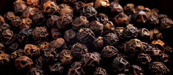 Black pepper grains as background close up