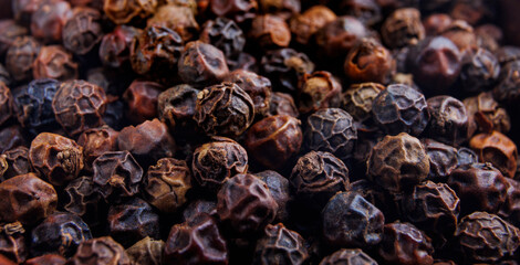 Black pepper grains as background close up