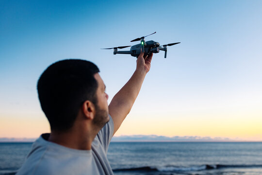 Black man launching drone near sea