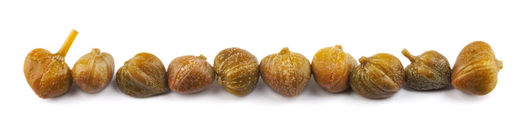 Capers isolated on white background. Full clipping path. A line of capers laid out in a row.