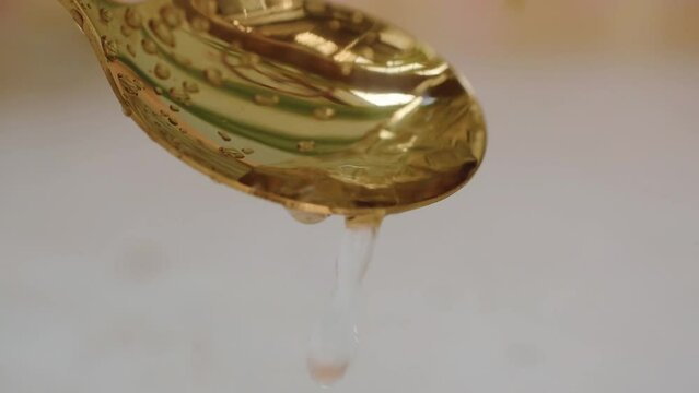 water drops pouring on golden spoon close-up blur background