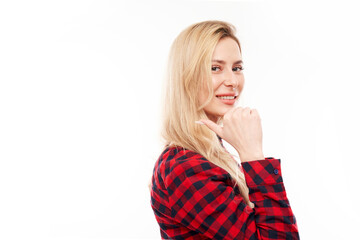 Joyful blonde girl in a plaid red shirt smiling points her finger at empty copy space for text or product isolated on white background, advertising banner