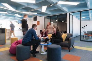 Multiethnic startup business team on meeting in a modern bright open space coworking office. Brainstorming, working on laptop. Group of coworkers walking around in motion blur. 