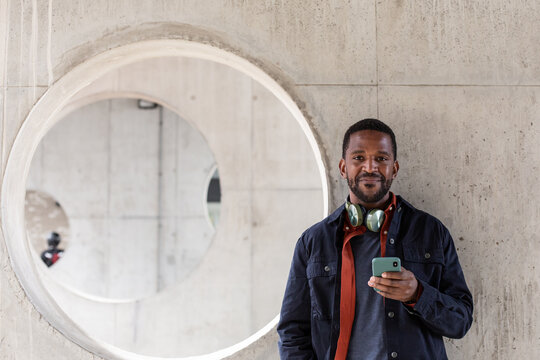 Portrait of African American mid adult man using smartphone with contemporary urban background