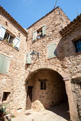 Fototapeta na wymiar Street of Tourtour with Stone houses topped with round tiles, a very touristic village in South of France. Tourtour nicknamed is “The village in the sky of Provence”