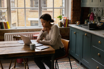 Young adult female at home paying bills and personal finances with a credit card