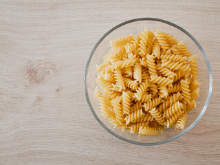 Spirelli / Fusilli / Spiral-Pasta in einer Glasschale auf einem Echtholztisch bei natürlichem Licht
