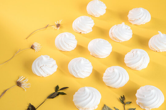 "Suspiros" or meringue, sweet made with egg whites, sugar and a few drops of lemon on a yellow background.