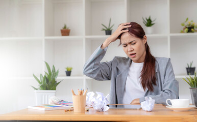 Mad Angry Stressed young asian female graphic designer or businesswoman with a crumpling paper on the table dissatisfied with her work, complained from her boss, getting a job problem.