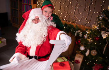 Fototapeta na wymiar Santa Claus with his Elf looking wish list