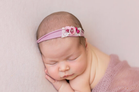 newborn child. little girl. newborn on a pink blanket. the first photo shoot. girl in a bandage with a flower