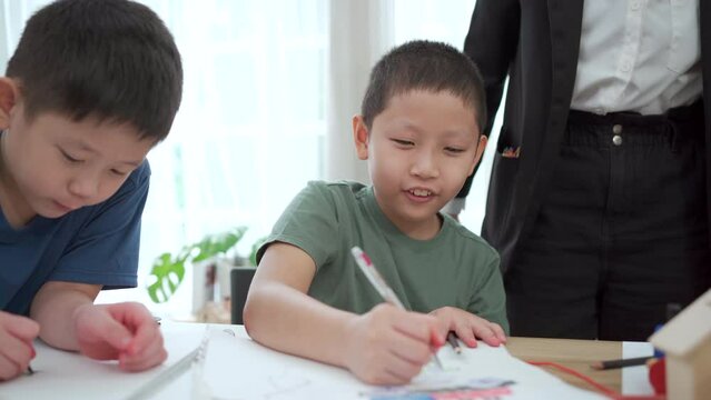 Kindergarten children enjoy drawing and painting in classroom.