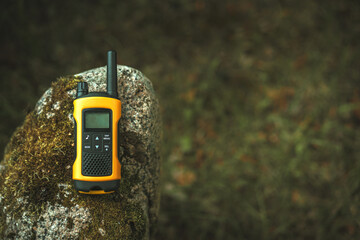 Orange walkie-talkie for negotiations and calls on a granite stone. Means of radio communication in...