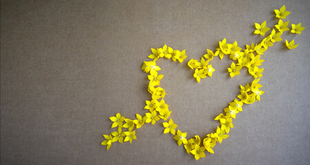 A heart pierced by an arrow on a sheet of cardboard made of yellow petals.A greeting card for Valentine's Day with your own hands. Background of flowers about a declaration of love.