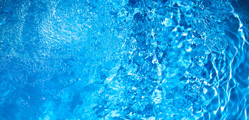 Background of blue water in the pool with small bubbles and splashes. Cooling blue background with...