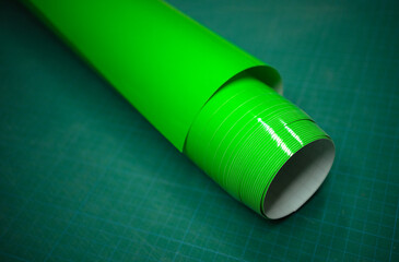 A roll of green self-adhesive film on the table. Film for cutting plotter. Production of outdoor...