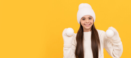 happy teen girl ion winter hat and gloves hold snowballs on yellow background, christmas. Banner of...
