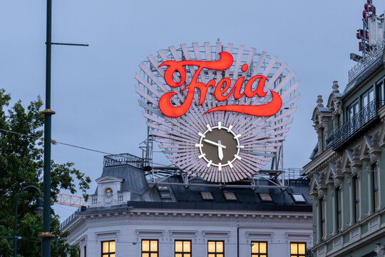 Oslo, Norway - October 14, 2022: Freia clock and Illuminated Freia sign 
at Egertorget square in downtown Oslo, Norway. Freia is a Norwegian chocolate sweets manufacturing company.
