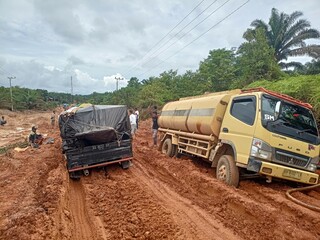 Kalimantan, Indonesia - October 18, 2022: Photo of damaged laterite roads resulting in long queues of heavily loaded vehicles.