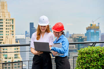Tow foreman woman working with laptop and tablet on rooftop with cityscape view