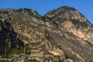 Autumn landscape in the mountains. Yellowed trees in autumn in the mountains of North Ossetia. Mountain gorges. View of the house high in the mountains. A village in the mountains.