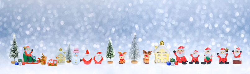 Many little Santa Claus dolls and Christmas decorations on snowing background in panoramic view, creative artwork Christmas celebration for web banner concept